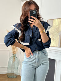 Cette chemise bleue Elyna allie élégance et confort avec son col classique et ses manches élastiques qui facilitent le mouvement. Les boutons sur toute la longueur permettent un enfilage pratique, tandis que le volant orné d'une broderie écrue apporte une touche délicate et raffinée.