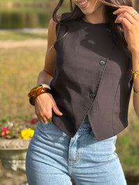 Le gilet de tailleur noir Leonie est la pièce parfaite pour compléter votre tenue formelle avec une touche de chic. Avec son design court et sans manches, ses boutons sur la longueur et son effet croisé sur le bas, il ajoute une sophistication à toute tenue. De plus, il est entièrement doublé pour un confort et une élégance optimaux. (Avec le gilet Leonie, vous serez la définition du style décontracté mais chic !)