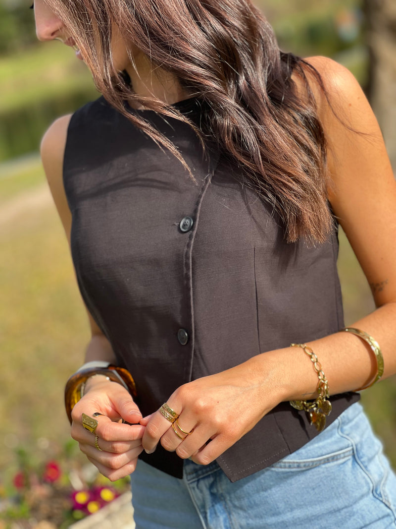 Le gilet de tailleur noir Leonie est la pièce parfaite pour compléter votre tenue formelle avec une touche de chic. Avec son design court et sans manches, ses boutons sur la longueur et son effet croisé sur le bas, il ajoute une sophistication à toute tenue. De plus, il est entièrement doublé pour un confort et une élégance optimaux. (Avec le gilet Leonie, vous serez la définition du style décontracté mais chic !)