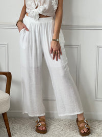 Pantalon Kerelys en teinte écru élégante avec taille élastique pour un confort optimal. Sa coupe large offre une silhouette décontractée et féminine. Doublé jusqu'à mi-longueur avec deux poches latérales pratiques. Sa légère transparence apporte une touche de délicatesse à votre tenue estivale.
