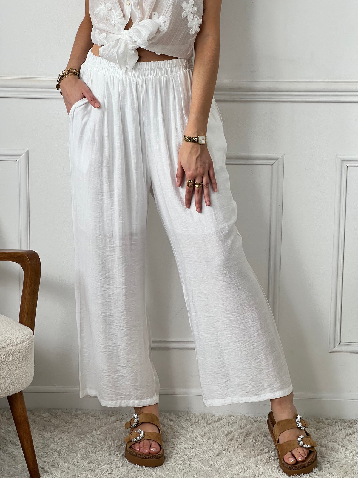 Pantalon Kerelys en teinte écru élégante avec taille élastique pour un confort optimal. Sa coupe large offre une silhouette décontractée et féminine. Doublé jusqu'à mi-longueur avec deux poches latérales pratiques. Sa légère transparence apporte une touche de délicatesse à votre tenue estivale.