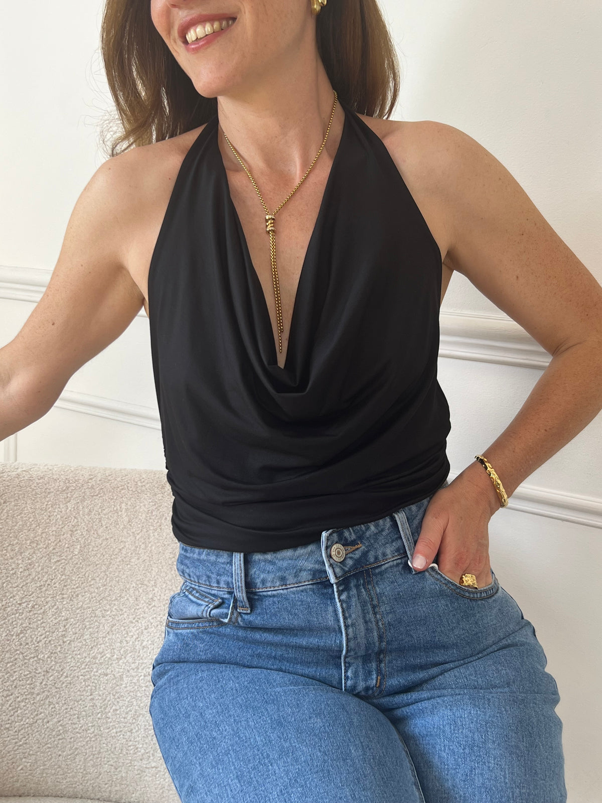 Ce top noir sans manches met en valeur votre silhouette avec son dos nu élégant et son drapé délicat. Sa coupe fluide assure un confort optimal tout en apportant une touche sophistiquée à vos tenues. Parfait pour les occasions où vous souhaitez allier style et aisance.