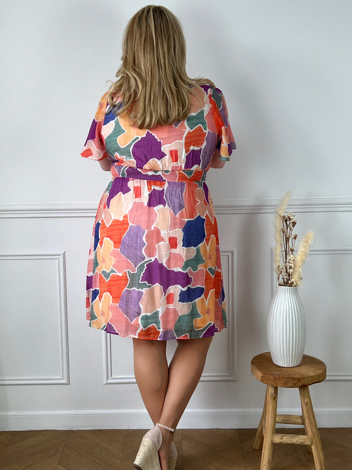 La robe courte Olympe est parfaite pour les femmes aux formes généreuses. Avec ses motifs colorés, elle apporte de la joie et de la vitalité à votre look. Les manches courtes et le col V mettent en valeur votre silhouette. La taille élastique au dos assure un confort optimal. Disponible en bleu, orange, écru, rose, violet, jaune et vert. La jupe est doublée pour un tomber parfait et la matière fine est agréable à porter. Ajoutez de la couleur à votre garde-robe avec la robe Olympe !