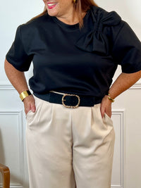 Tee-shirt noir grande taille pour femme, ce tee-shirt à manches courtes est doté d’un col rond et d’un nœud sur le devant pour une touche féminine. Confectionné dans une matière épaisse pour un tombé structuré. Couleur noir, idéale pour la mi-saison.