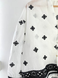 Offrez-vous un look élégant avec la chemise Kea en coton écrue et noire pour femme. Avec son col V et ses motifs subtils, elle est idéale pour toutes les occasions. Légèrement transparente, elle est boutonnée sur la longueur et aux poignets avec un détail broderie noire.