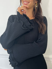 La robe longue noir Esther est un mariage parfait de chic et de confort. Avec ses manches longues et son col rond, elle assure une élégance intemporelle. Mais le dos nu avec lacets croisés et les volants aux manches et au bas de la robe ajoutent une touche ludique et originale. Soyez prête à faire tourner les têtes avec cette robe unique !