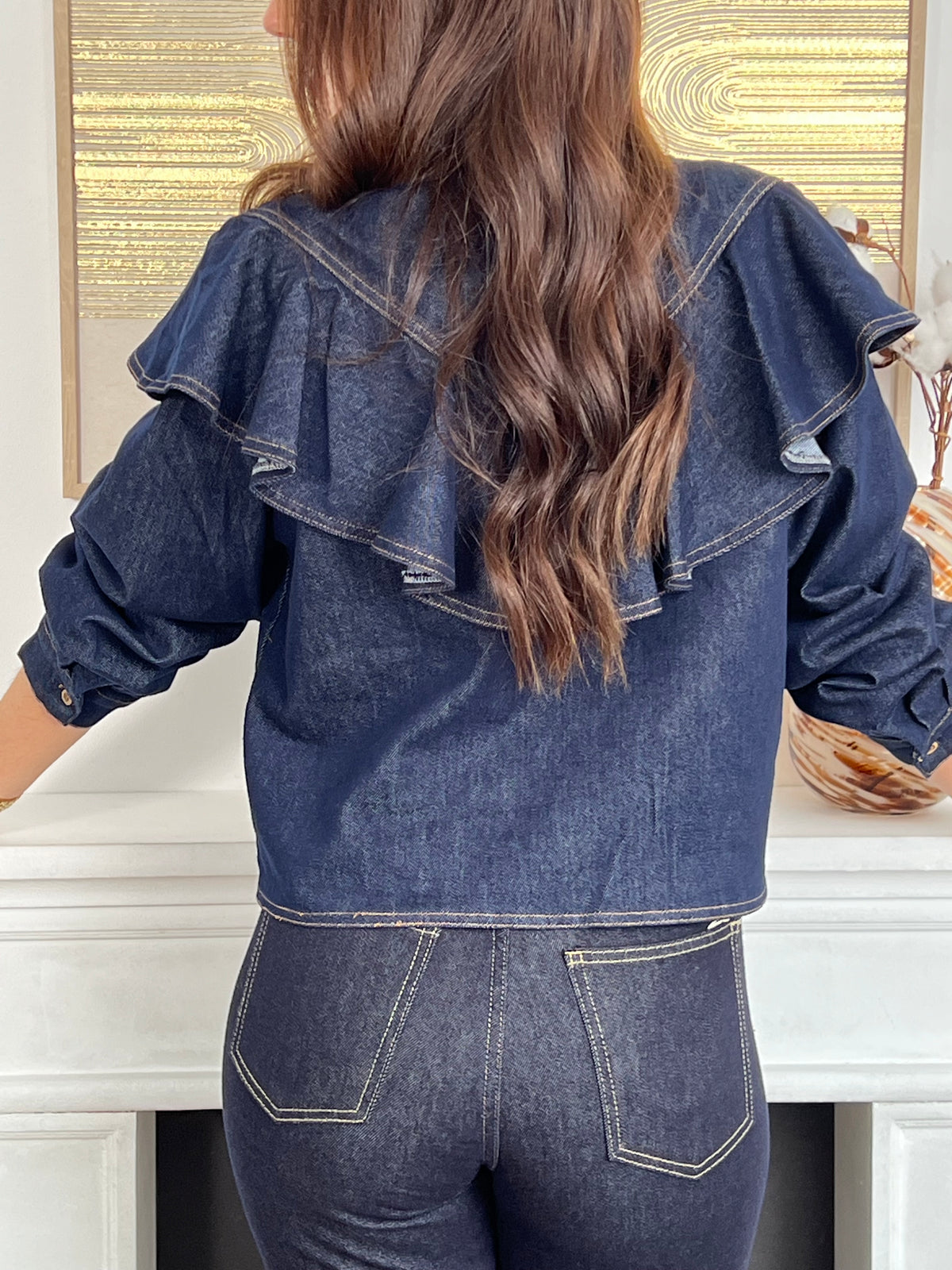 Chemise courte bleu brut pour femme, confectionnée en 100 % coton pour un confort naturel. Dotée de manches longues, d’un col chemise et de jolis volants sur le devant, elle offre un style à la fois féminin et moderne. Ses boutons ton sur ton et ses coutures camel apportent une touche raffinée et tendance.