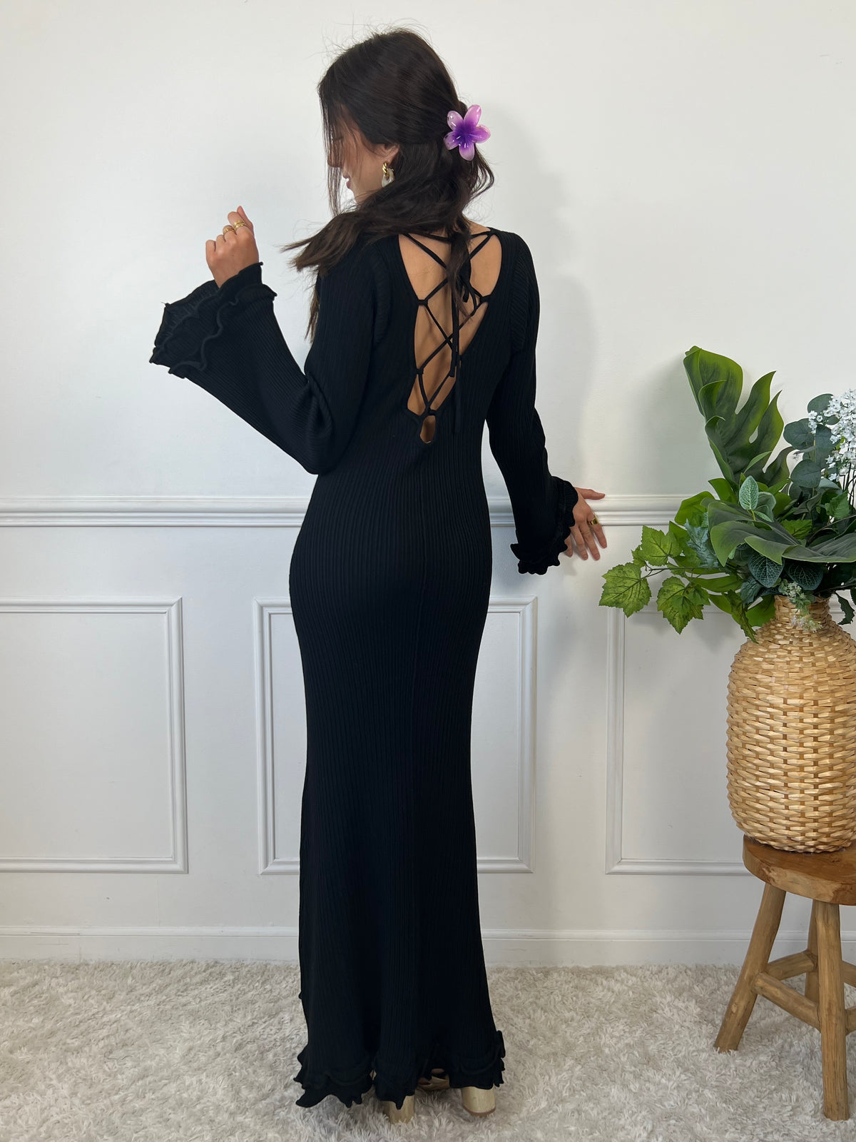 La robe longue noir Esther est un mariage parfait de chic et de confort. Avec ses manches longues et son col rond, elle assure une élégance intemporelle. Mais le dos nu avec lacets croisés et les volants aux manches et au bas de la robe ajoutent une touche ludique et originale. Soyez prête à faire tourner les têtes avec cette robe unique !