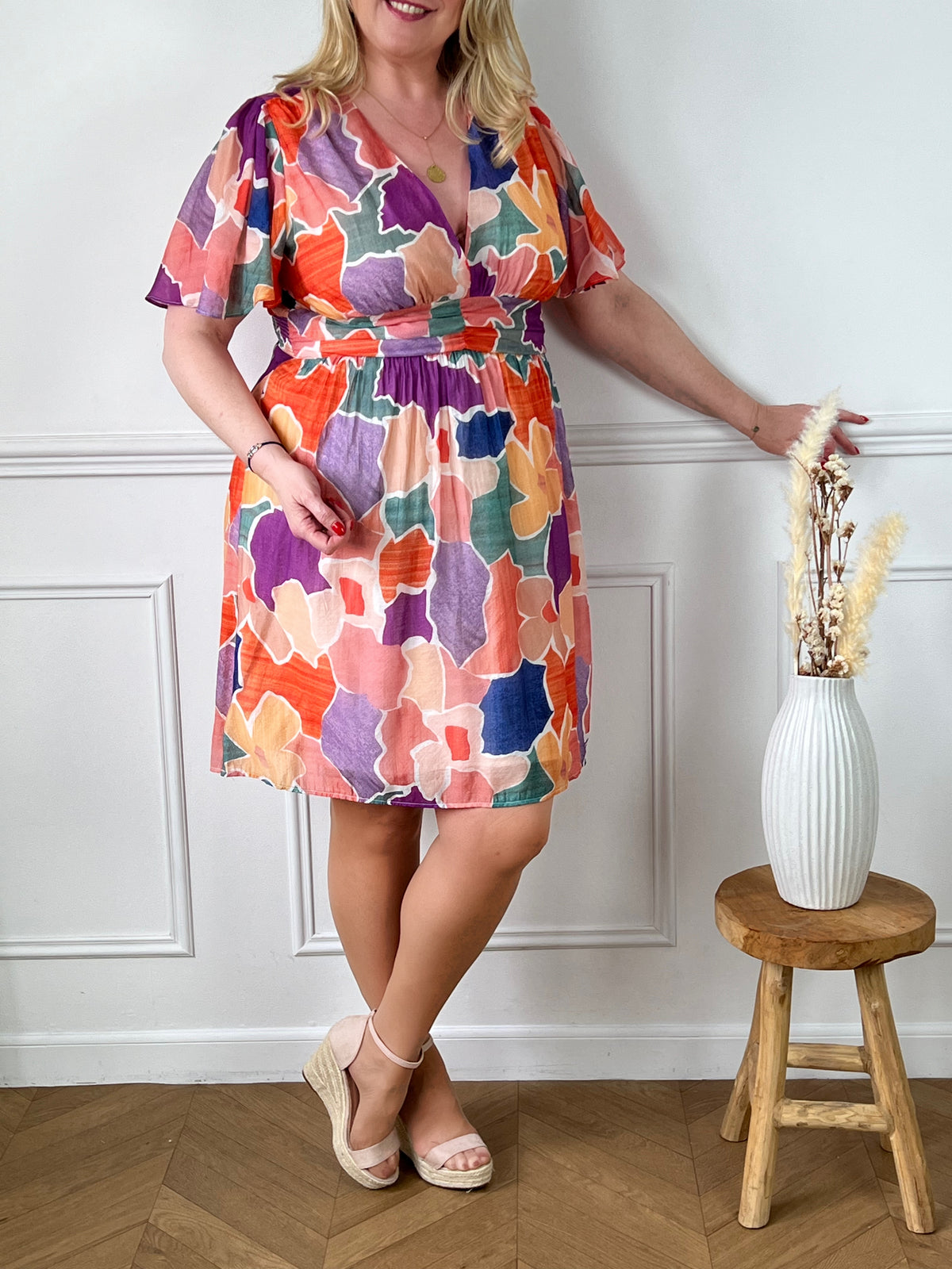 La robe courte Olympe est parfaite pour les femmes aux formes généreuses. Avec ses motifs colorés, elle apporte de la joie et de la vitalité à votre look. Les manches courtes et le col V mettent en valeur votre silhouette. La taille élastique au dos assure un confort optimal. Disponible en bleu, orange, écru, rose, violet, jaune et vert. La jupe est doublée pour un tomber parfait et la matière fine est agréable à porter. Ajoutez de la couleur à votre garde-robe avec la robe Olympe !