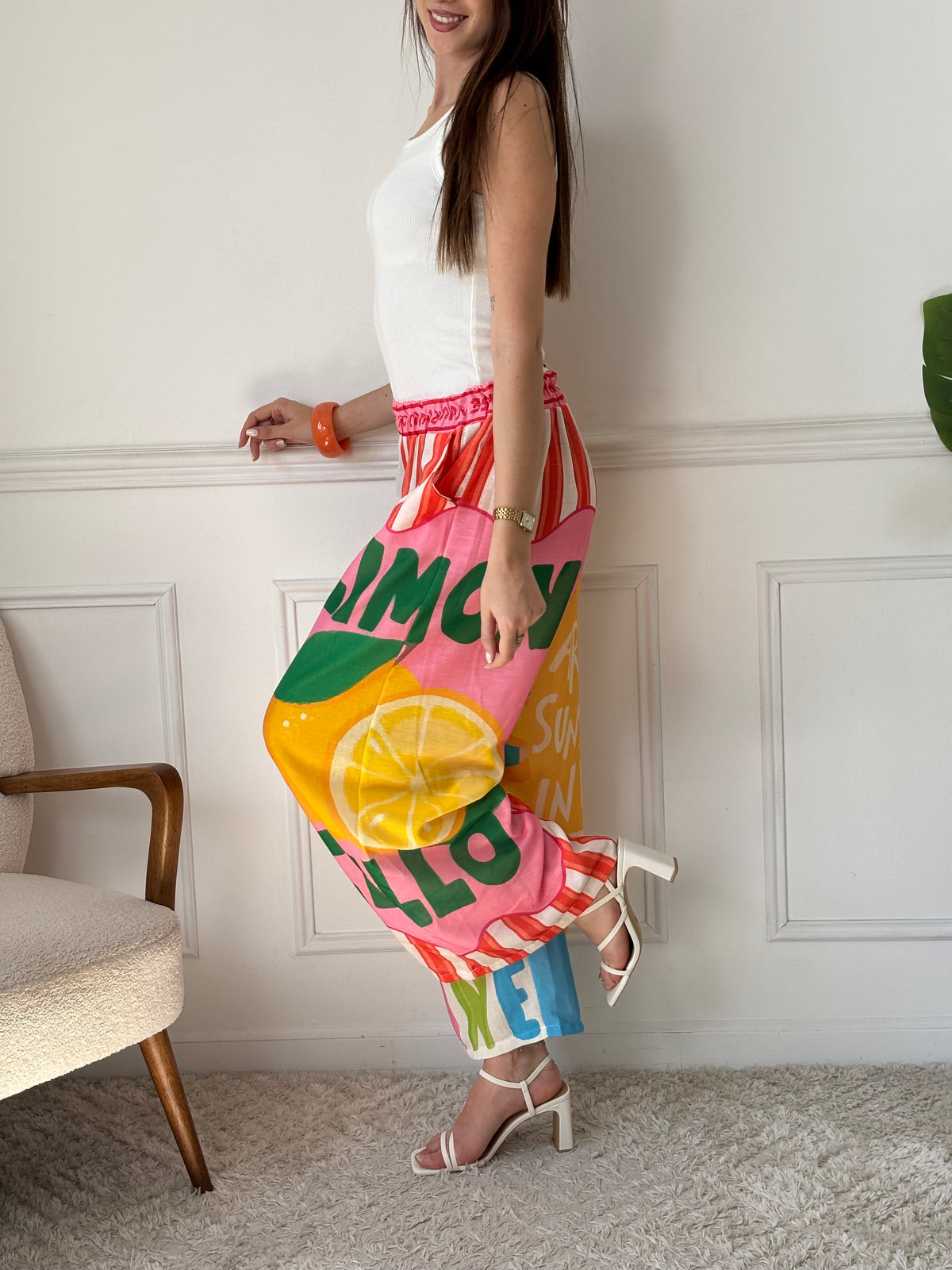 Ce pantalon en lin aux motifs colorés et inspirés des vacances respire la bonne humeur. Avec ses inscriptions comme "You are my Sunshine", "Lemoncello" ou "You are the Sunshine in everyday", il invite à la détente et à l’évasion. Ses teintes de beige, vert, orange, rose, rouge et bleu en font une pièce pétillante, idéale pour un look estival plein de charme et de légèreté.