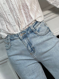 Jean bleu clair pour femme au style moderne et confortable, idéal pour un look tendance au quotidien. Ce modèle est doté de deux poches à l’avant et à l’arrière, de passants pour ceinture, ainsi que d’une fermeture éclair et d’un bouton pratique. Les détails tressés sur le devant apportent une touche originale et élégante à ce jean bleu incontournable.