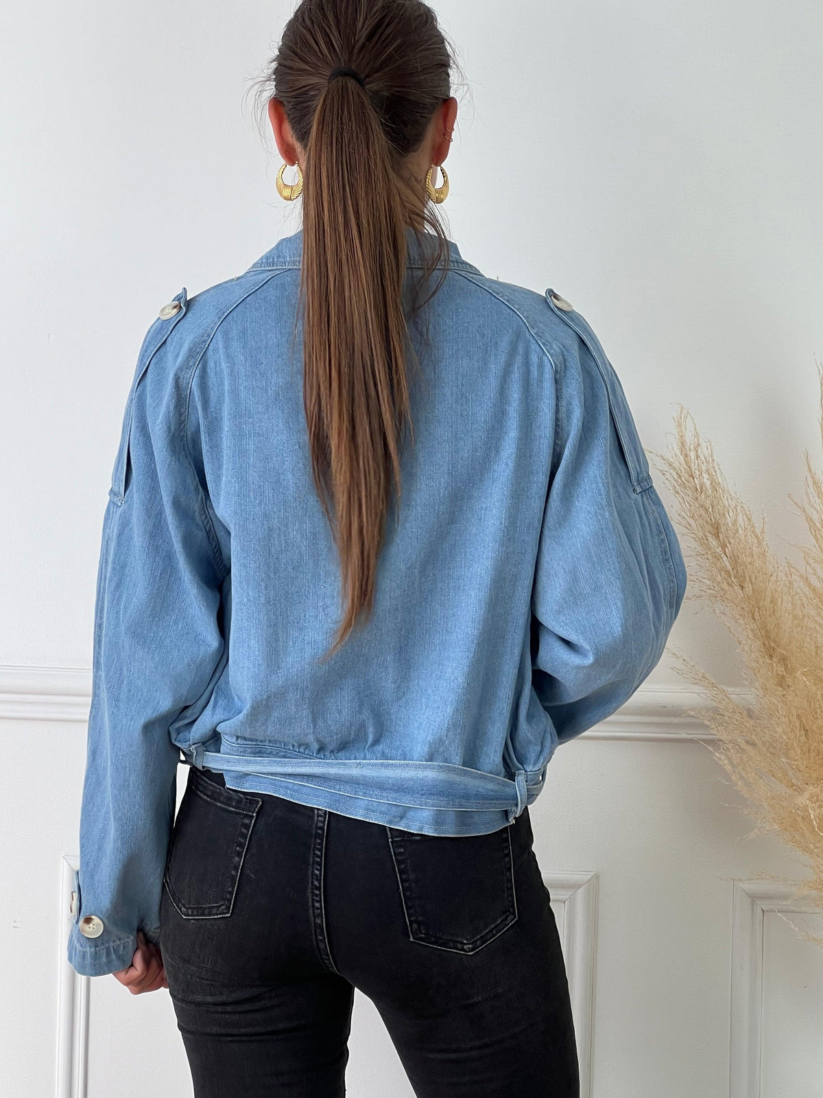Veste courte en jean bleue Manches longues Boutons sur la longueur et aux poignets 2 poches latérales Ceinture amovible avec passants Boutons sur les poches, à la poitrine, aux épaules et aux poignets Couleur : bleu clair Composition : 100% Coton Made in P.C.R