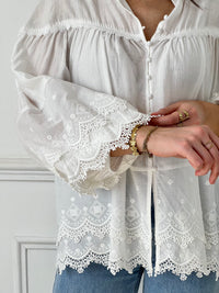 Cette blouse écrue Auriola apporte une touche de sophistication à votre garde-robe avec son élégante broderie et son col rond. Les manches longues et les poignets élastiques offrent un confort incomparable, tandis que les boutons sur le devant ajoutent une touche de style.