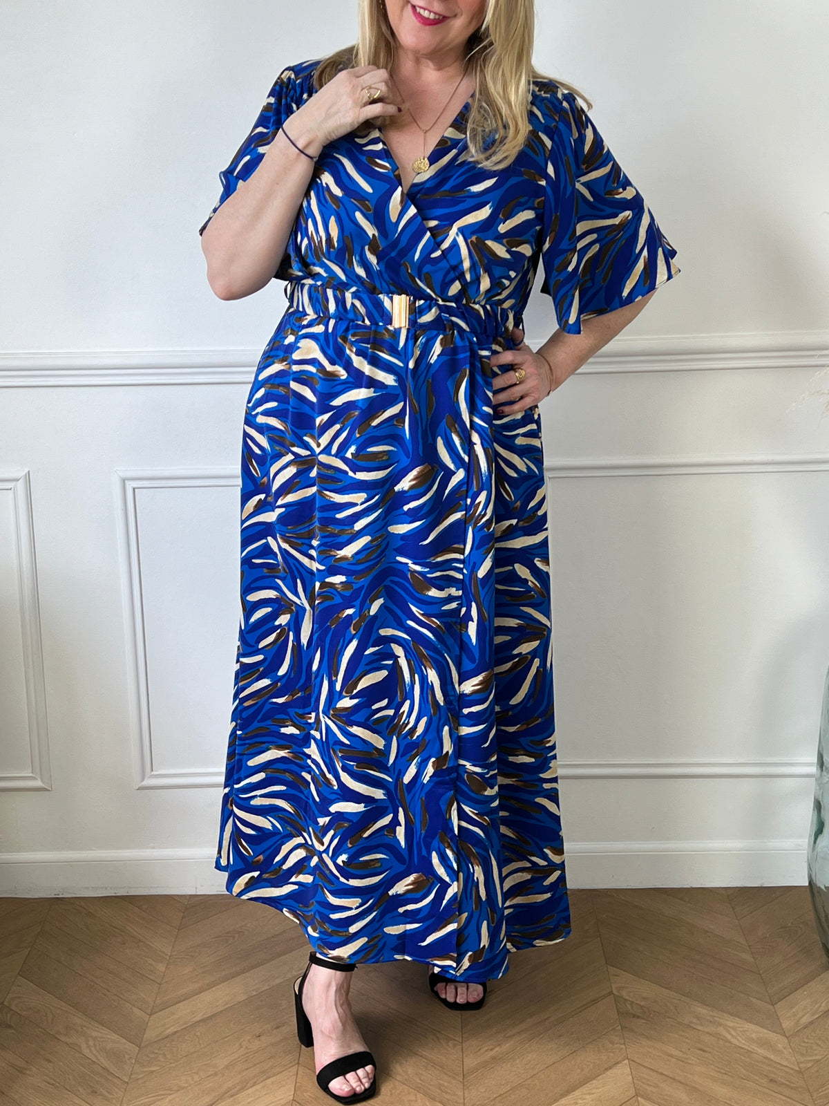 Cette robe s'étend jusqu'aux pieds et est ornée de motifs bleus, ce qui lui confère un style distinctif. La ceinture peut être utilisée pour marquer la taille et ajouter une touche de structure à la silhouette. Cette tenue est parfaite pour des occasions spéciales ou pour un look décontracté mais chic.