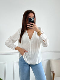 Délicate blouse Solène en gaze de coton écru, ornée de broderies élégantes aux épaules et aux manches. Son col V et ses manches longues apportent une touche de féminité intemporelle. Confectionnée en 100% coton, elle allie légèreté et confort pour sublimer votre silhouette avec raffinement.