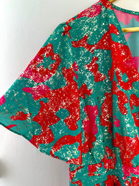 Plongez dans un tourbillon de couleurs avec cette robe vibrante, mêlant des tons de vert, de rose et de rouge. Sa palette audacieuse évoque la joie et la vitalité, tandis que sa coupe flatteuse met en valeur votre silhouette avec élégance.