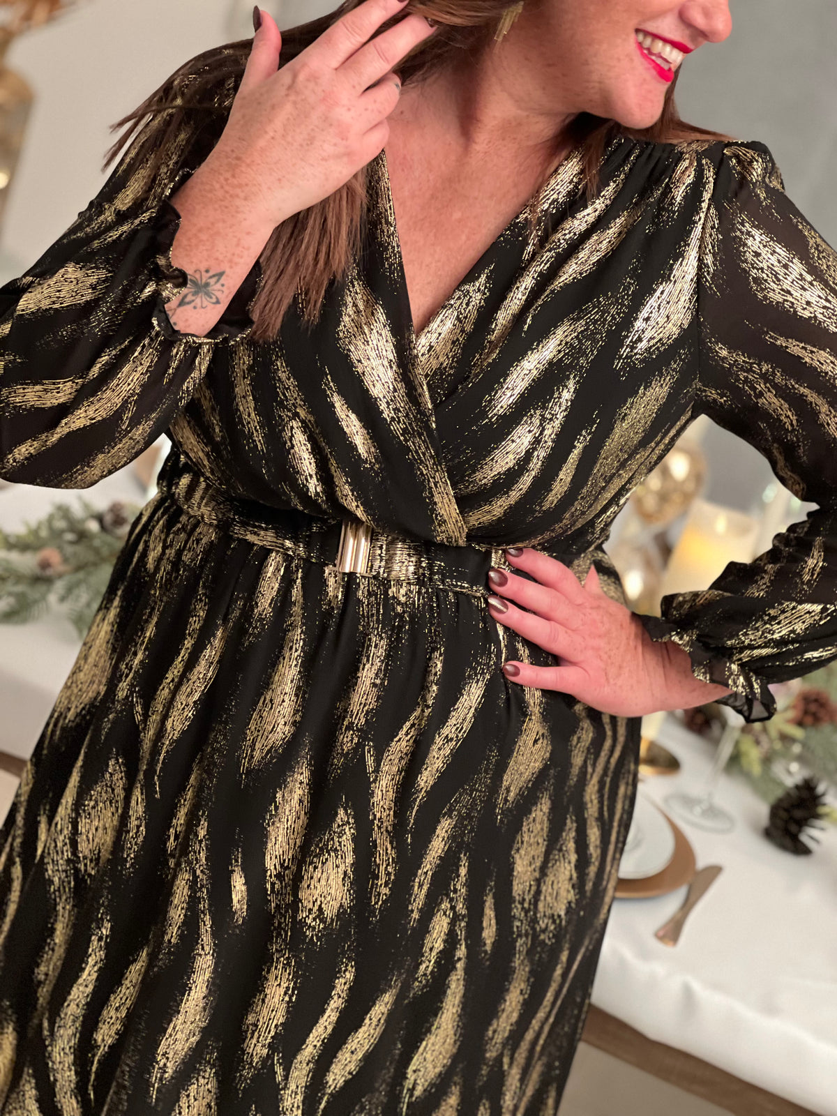 Robe festive Laina, l'allure sophistiquée pour vos soirées. Cette création élégante allie le noir profond et les touches dorées pour une présence rayonnante. Le col cache-cœur flatteuse épouse votre silhouette tandis que la taille élastique offre un confort optimal.