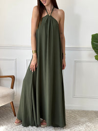 Adoptez une allure audacieuse avec cette robe longue kaki Adeje. Son col montant réglable, orné d’un détail doré, apporte une touche sophistiquée tandis que l’élastique au dos assure un confort parfait. Sans manches et à la coupe ample, elle offre une liberté de mouvement idéale pour affirmer votre style avec assurance.&nbsp;