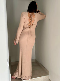 La robe longue beige Esther est un mariage parfait de chic et de confort. Avec ses manches longues et son col rond, elle assure une élégance intemporelle. Mais le dos nu avec lacets croisés et les volants aux manches et au bas de la robe ajoutent une touche ludique et originale. Soyez prête à faire tourner les têtes avec cette robe unique !