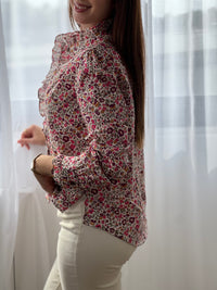 Cette chemise beige "Mia" avec motif floral offre une élégance délicate grâce à ses manches longues et ses volants raffinés au col, sur la longueur et aux manches.