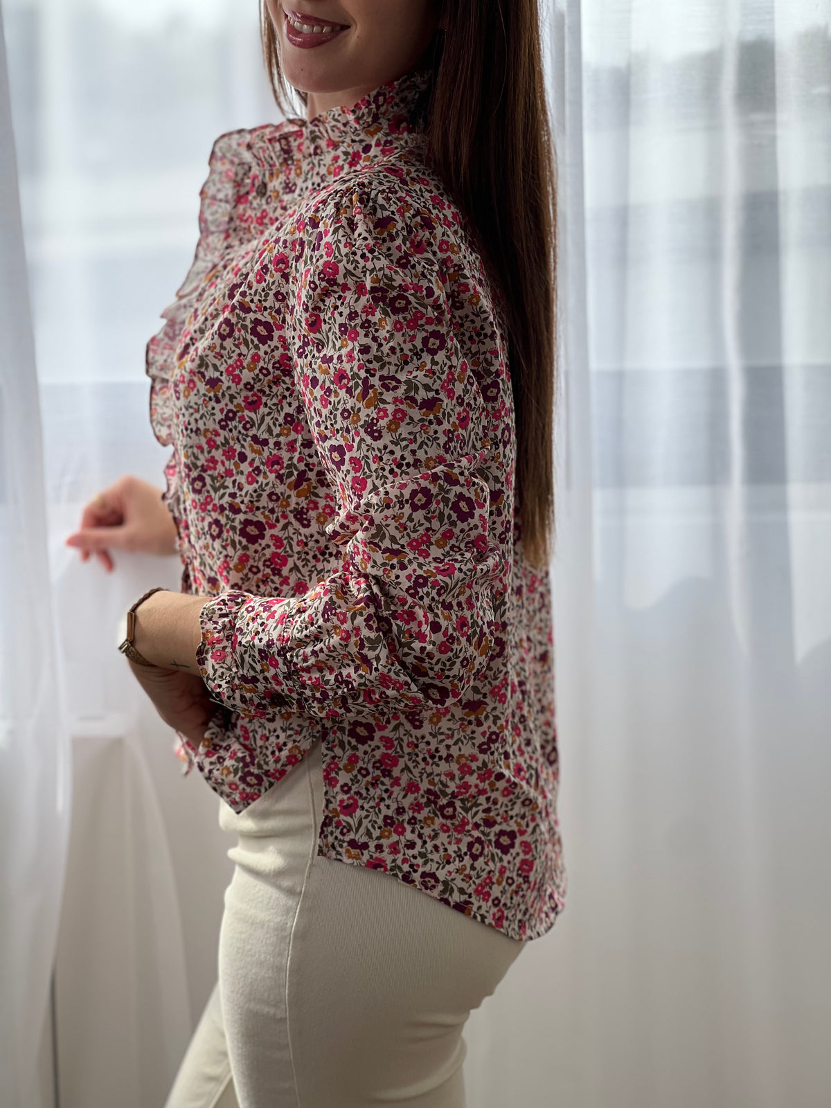 Cette chemise beige "Mia" avec motif floral offre une élégance délicate grâce à ses manches longues et ses volants raffinés au col, sur la longueur et aux manches.