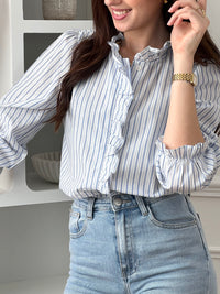 Adoptez cette chemise bleue et écrue femme, élégante et féminine. Dotée de manches longues, d’un col rond et de boutons sur toute la longueur, elle se distingue par ses volants au col et le long de la fermeture. Ses rayures verticales bleues et écrues apportent une touche raffinée et allongent la silhouette.