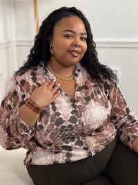 La chemise Elma en marron offre style et confort pour les femmes grande taille. Avec ses manches longues, son col V à volants et son motif floral rehaussé de lurex doré, elle conjugue élégance et féminité. Doublée de la poitrine au bas et fermée par des boutons.