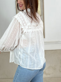 Chemise Angele en coton 100% pour les femmes. Manches bouffantes, col volant et broderie ajourée confèrent à cette pièce écrue une élégance intemporelle. Légèrement transparente, elle se porte avec aisance au quotidien comme en occasion.