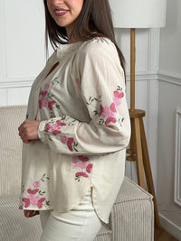 Confectionnée dans une matière légère et légèrement transparente, elle offre confort et élégance au quotidien. Ses manches longues et son col rond classique se complètent parfaitement avec des boutons discrets sur toute la longueur. Les motifs fleurs roses et vertes apportent une touche de douceur et de féminité à cette chemise polyvalente, idéale pour créer des looks décontractés ou plus raffinés selon vos envies.