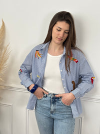 Découvrez Adia, notre chemise en coton pensée pour vous. Avec ses manches longues et son col chemise classique, elle allie élégance et confort. Les rayures verticales bleues et écrues créent une base intemporelle, sublimée par des motifs brodés colorés qui ajoutent du caractère.