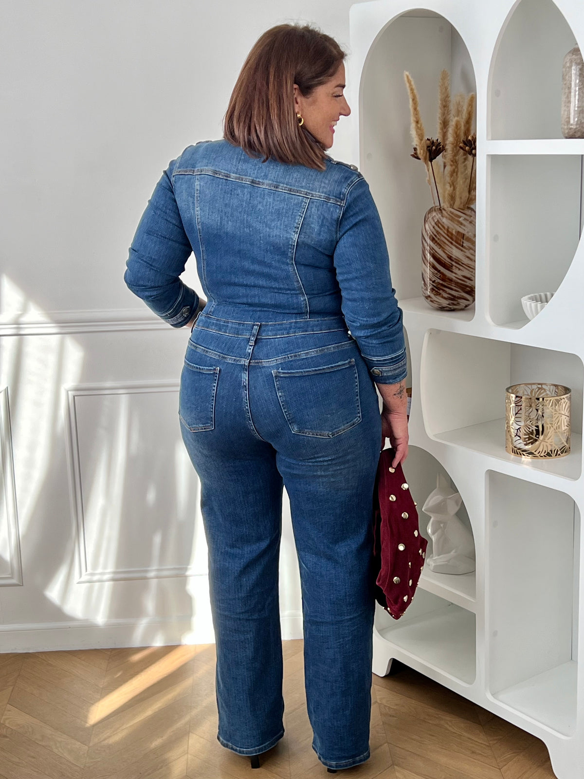 Combinaison en jean bleu grande taille vue de dos, montrant les poches arrière et les passants à la taille – Nella | Loïcia