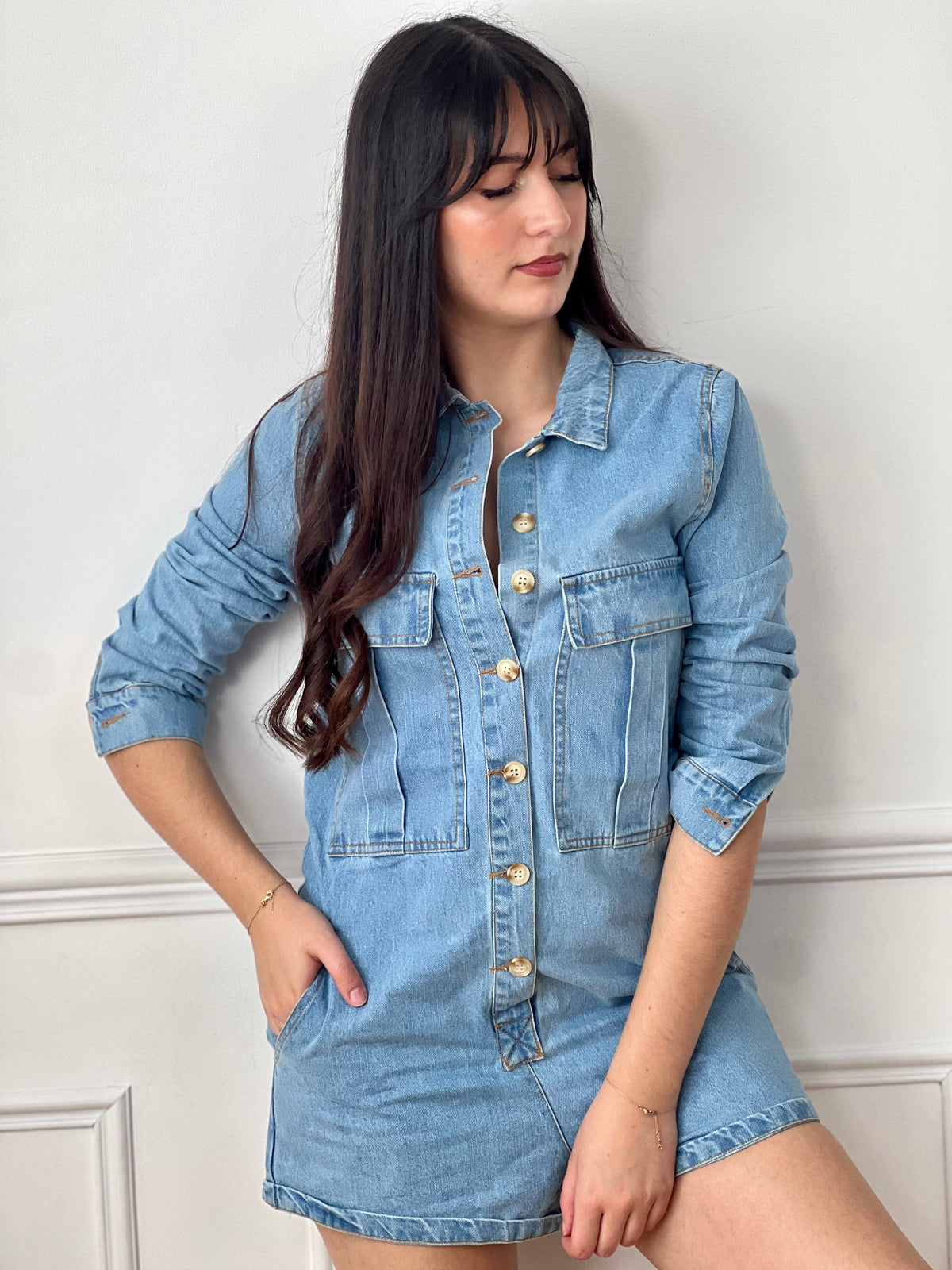 Combishort en jean bleu femme, idéal pour un look tendance et décontracté. Avec ses manches longues, son col chemise et ses boutons sur toute la longueur, il allie style et praticité. Doté de quatre poches à l’avant et de deux poches à l’arrière, il offre un côté fonctionnel au quotidien. Ses coutures camel apportent une touche contrastée et moderne. Un indispensable pour une tenue casual chic.