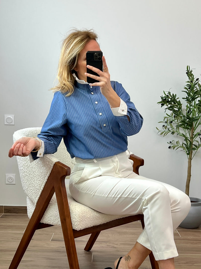 Découvrez notre chemise bleue Joelia, confectionnée pour les femmes raffinées. Les manches longues et les boutons en détail apportent une touche sophistiquée, tandis que le col montant et les volants écrus ajoutent une note d'élégance. Son motif rayé bleu et blanc complète son look exclusif.