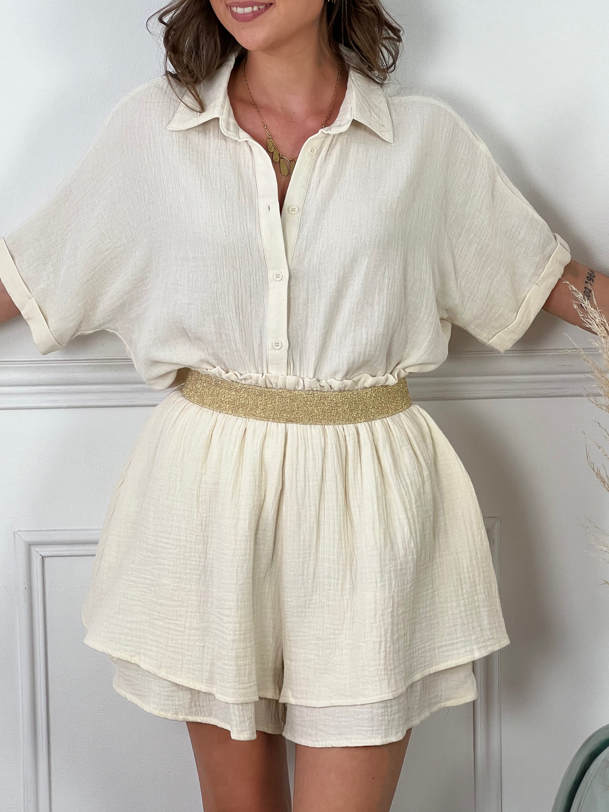 Découvrez ce magnifique short beige, agrémenté de volants délicats pour une touche féminine et élégante. La ceinture dorée rehausse subtilement la taille, ajoutant une note chic et sophistiquée. Idéal pour les journées d'été, ce short est parfait pour un look raffiné et tendance, que ce soit pour une sortie entre amis ou une occasion spéciale.