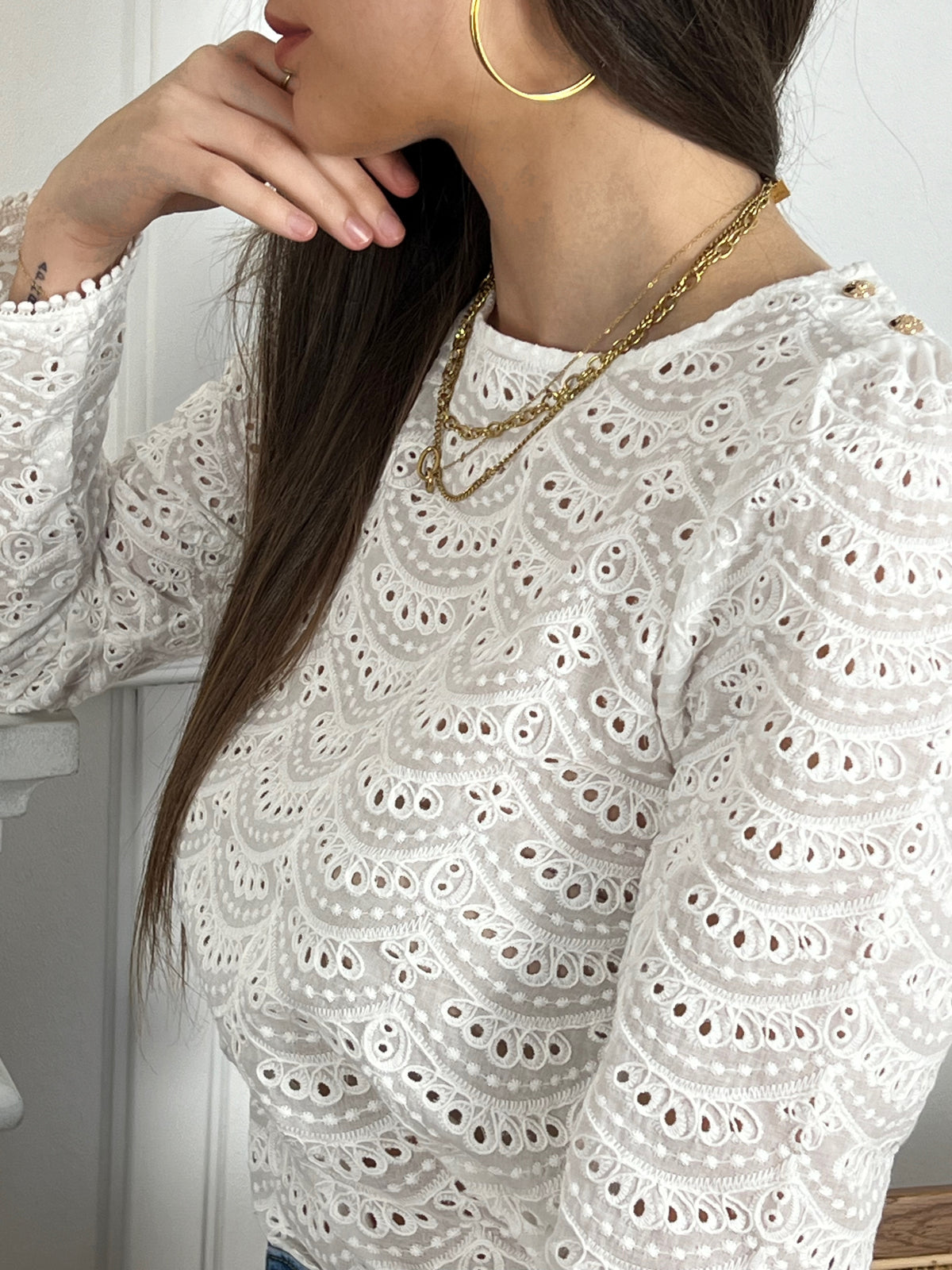 La blouse écru ajourée avec boutons au dos allie élégance et subtilité. Sa couleur douce et ses détails ajourés lui confèrent un charme intemporel. C'est une pièce versatile qui peut être portée avec style pour diverses occasions.