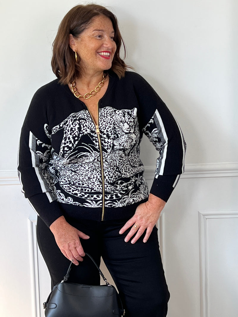 Gilet noir Elvira grande taille porté de face, avec motif léopard blanc, fermeture zippée dorée et bandes blanches sur les manches.
