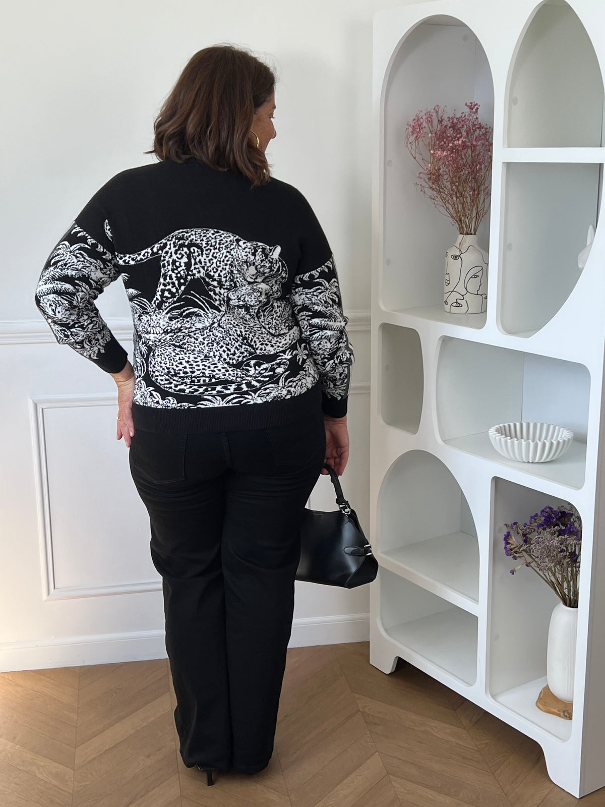 Gilet noir Elvira porté de dos, avec grand motif léopard blanc et motifs végétaux sur le dos et les manches