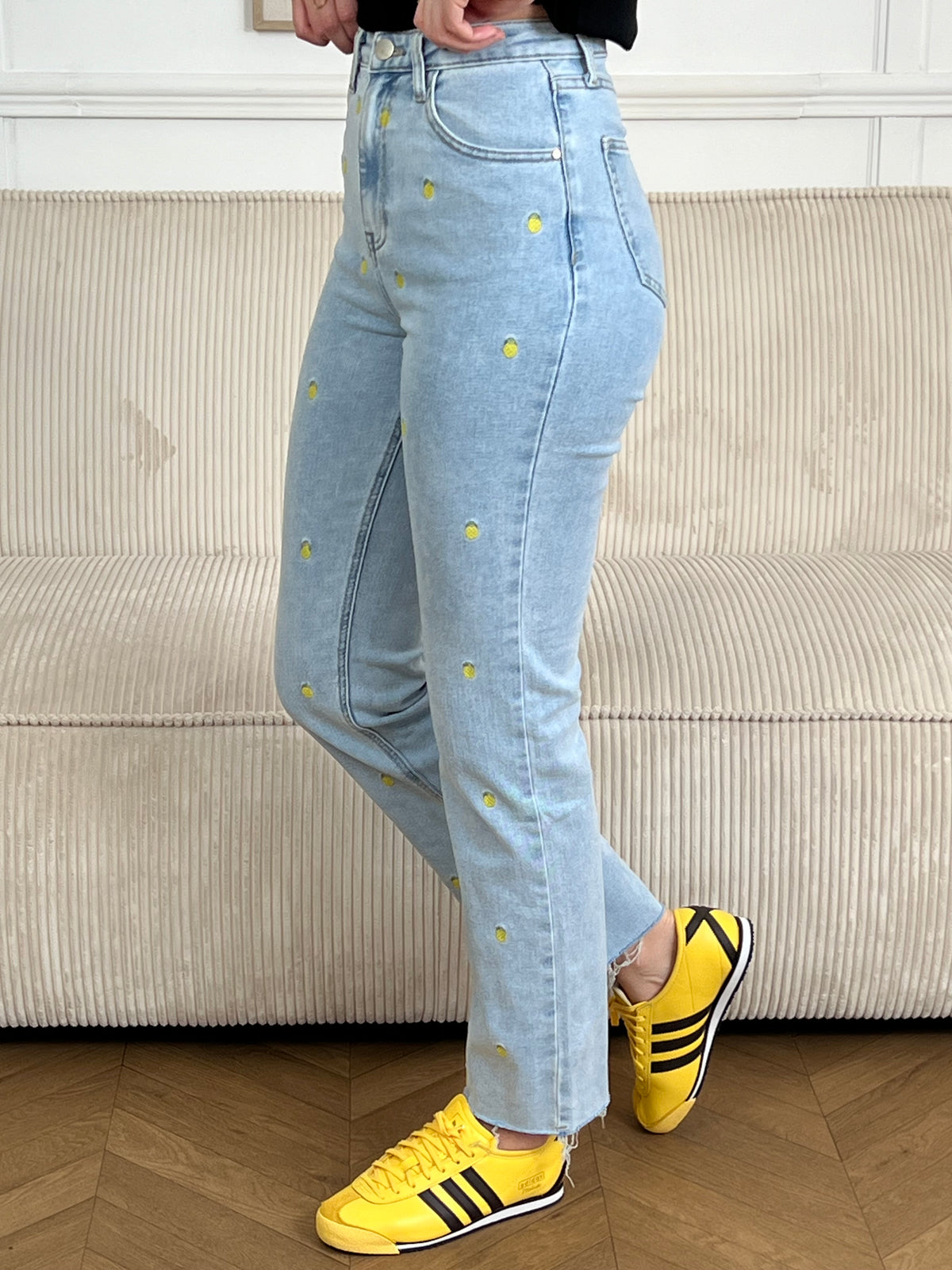 Jean bleu femme coupe straight intemporelle, agrémenté de motifs ananas brodés en jaune et vert pour une touche de couleur ludique. Fermeture à zip et bouton, quatre poches pratiques. Confectionné en coton, ce jean allie confort et style décontracté, parfait pour un look casual chic au quotidien.