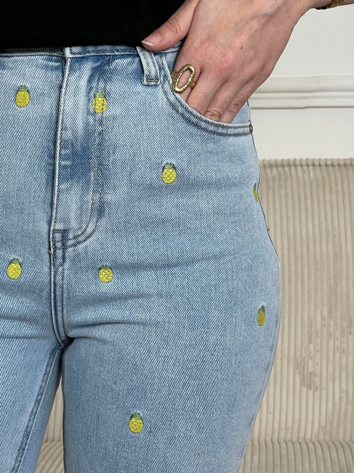 Jean bleu femme coupe straight intemporelle, agrémenté de motifs ananas brodés en jaune et vert pour une touche de couleur ludique. Fermeture à zip et bouton, quatre poches pratiques. Confectionné en coton, ce jean allie confort et style décontracté, parfait pour un look casual chic au quotidien.