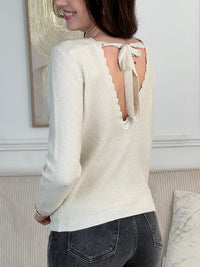 Le pull Celestina combine élégance et sensualité avec son dos nu en V à lien noué et ses manches longues. Orné de fil lurex doré, ce pull beige et doré brille de mille feux. Son col rond festonné ajoute une touche de raffinement pour des occasions spéciales.