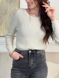 Le pull Celestina combine élégance et sensualité avec son dos nu en V à lien noué et ses manches longues. Orné de fil lurex doré, ce pull beige et doré brille de mille feux. Son col rond festonné ajoute une touche de raffinement pour des occasions spéciales.