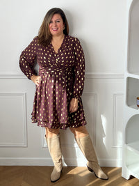 Robe courte marron Faustina grande taille portée de face, avec une main sur la hanche et des bottes beiges.