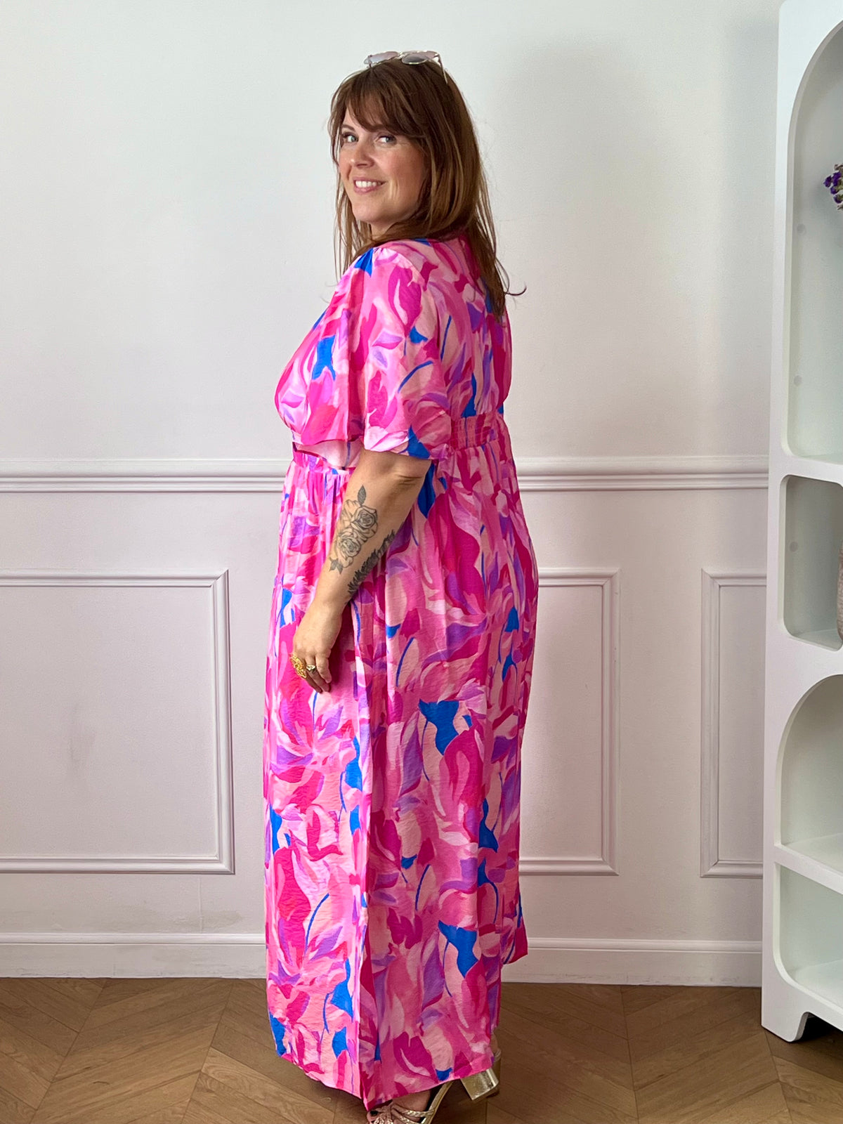 Laissez-vous séduire par cette robe longue grande taille au style féminin et coloré. Son col V et ses manches courtes apportent une touche d’élégance décontractée, tandis que sa taille élastiquée au dos assure un confort optimal et une belle mise en valeur de la silhouette. Sur un fond écru lumineux, ses motifs aux nuances rose fuchsia, jaune, bleu et violet apportent fraîcheur et originalité, faisant de cette robe la pièce idéale pour la saison.