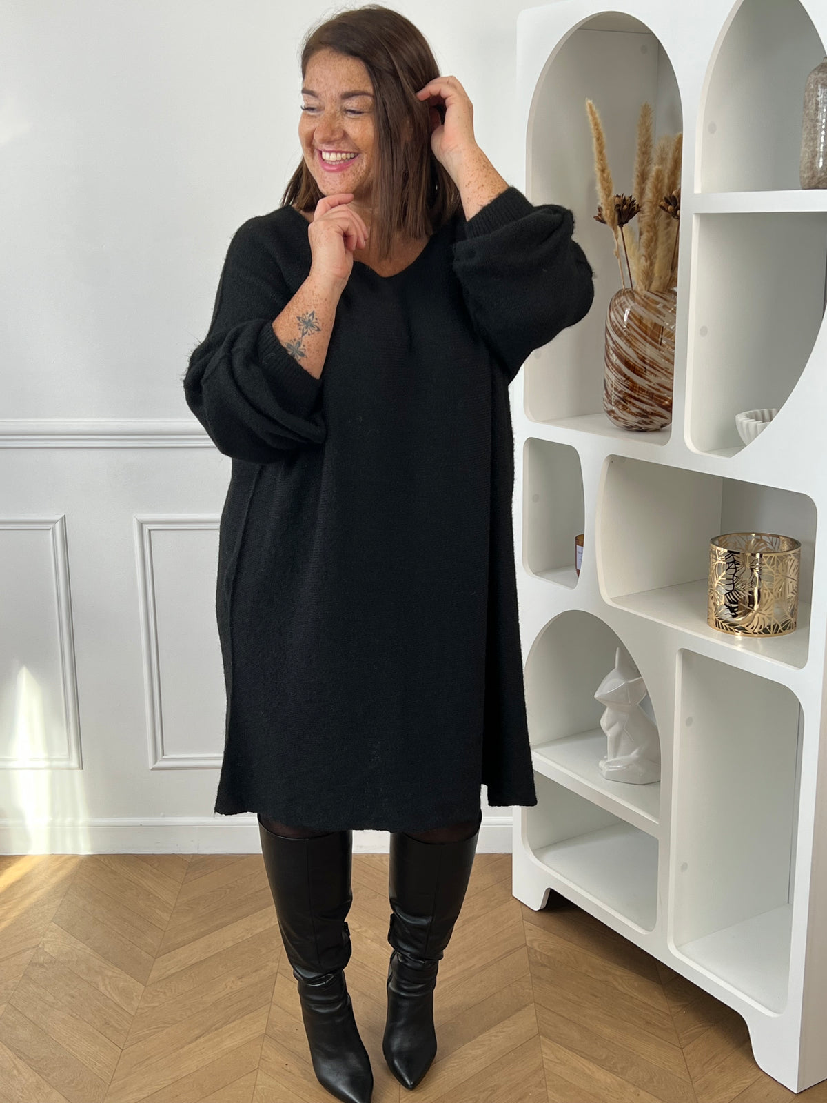 Robe pull noire grande taille à manches longues, portée de face avec des bottes hautes noires – Jessie | Loïcia