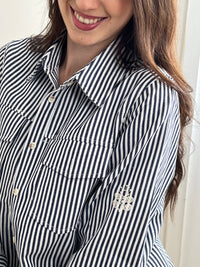 Découvrez la surchemise Anabelle, une pièce incontournable pour un style décontracté et élégant. Confectionnée en coton, elle arbore des rayures verticales subtiles dans les tons écru et bleu. Son col chemise classique et ses manches longues offrent une allure intemporelle, tandis que les motifs brodés délicats sur le devant et les manches ajoutent une touche de caractère.