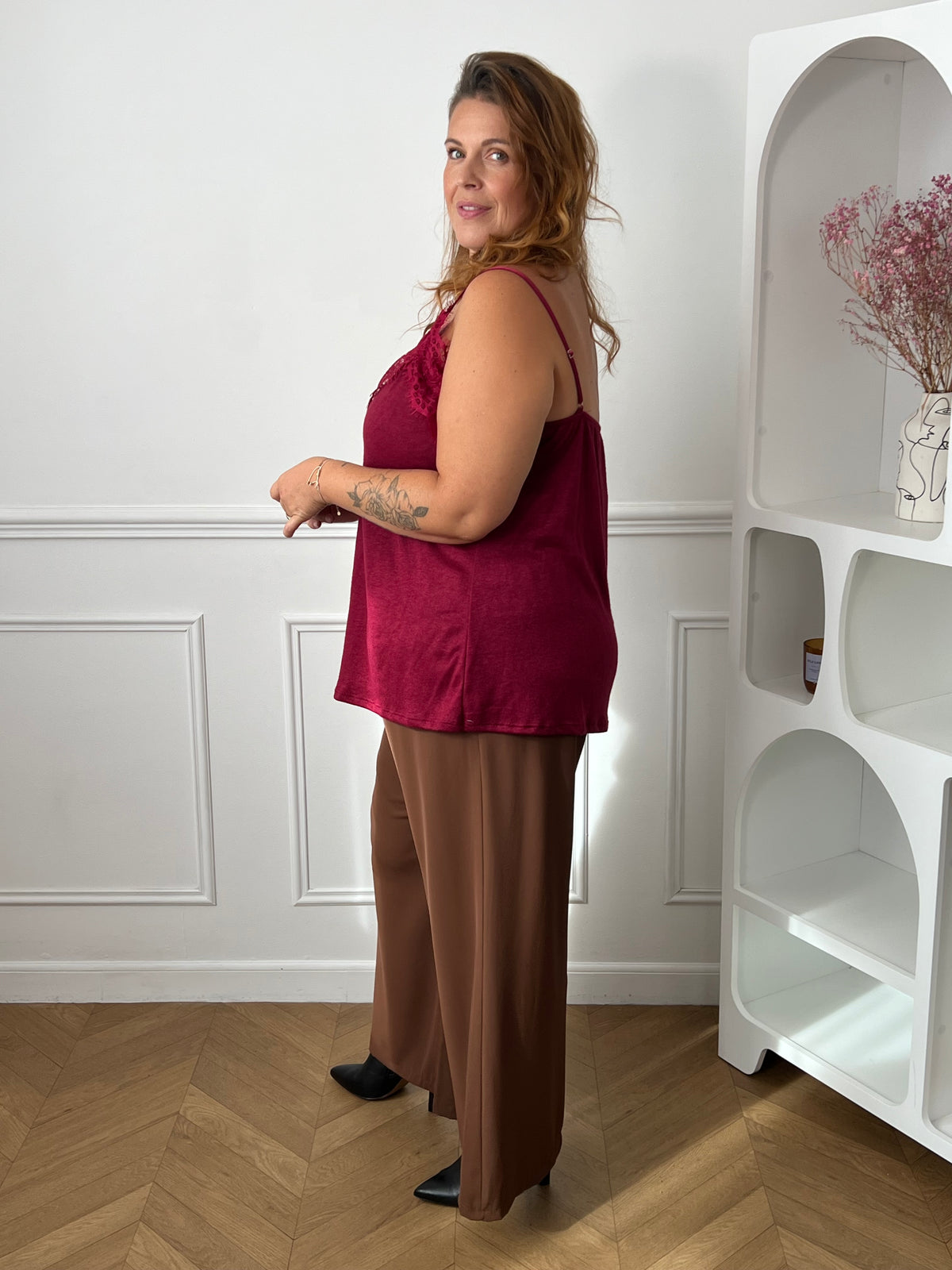 Top bordeaux vu de trois quarts dos, montrant ses fines bretelles et son tombé fluide sur un pantalon marron – Maelie | Loïcia