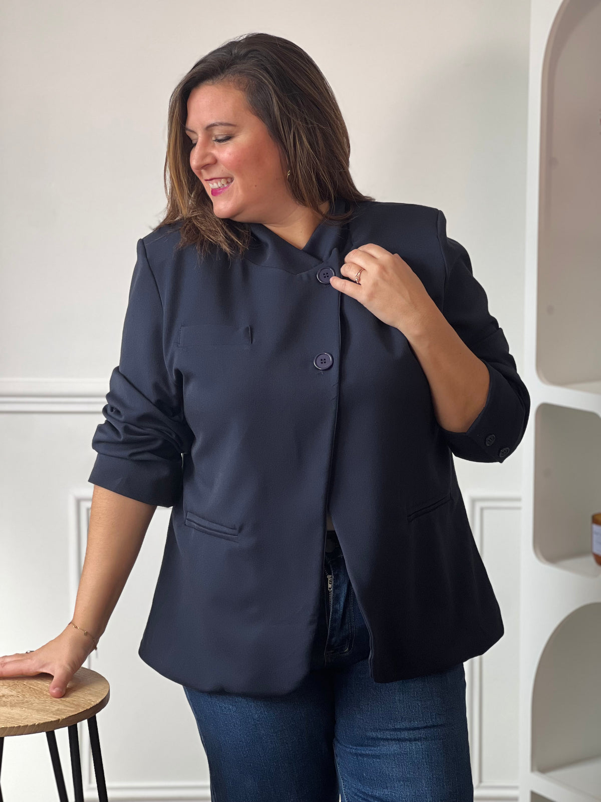 Vue rapprochée de la veste bleu marine Loen portée boutonnée, avec poches passepoilées et manches remontées.