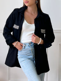 VESTE NOIRE EN COTON FEMME Veste manches longues Boutons sur la longueur et aux poignets 2 poches au niveau de la poitrine et 2 poches latérales à découdre Strass sur les poches à la poitrine Couleur : noir Composition : 100% Coton