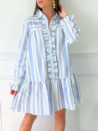 ROBE BLEUE ET BLANCHE À VOLANTS Robe chemise Volants et boutons sur la longueur Col chemise Elastiquée aux poignets Coupe ample Motif rayure écrue et grise Couleurs : bleu et ecru Composition : 60% Coton 30% Viscose Lavage à la main
