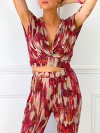 TOP FEMME SANS MANCHES PAILLETE  Top sans manches Col V devant Effet croisé sur le devant Pailleté sur tout le top Couleur : beige avec motifs rose, bordeaux, orange Matière légèrement extensible Elastique à l’arrière de la taille
